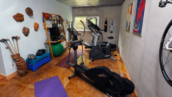 A lower-level workout room has athletic-themed decor and an industrial feel.