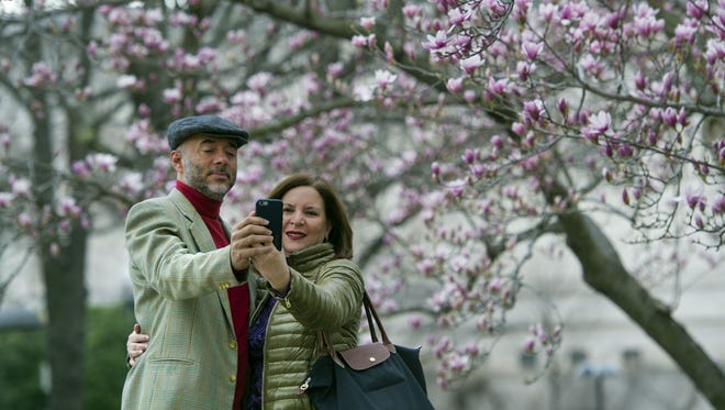 Fidelio Desbradel and his wife, Leonor Desbradel, of the Dominican Republic, take a selfie in front of a Tulip Magnolia tree in Washington. A selfie reveals more than whether it’s a good hair day. A company has developed facial analytics technology to help estimate life expectancy by analyzing your face from a photo you upload online. Life insurance companies are interested in the product because it may help them reduce your wait for coverage and boost their sales.