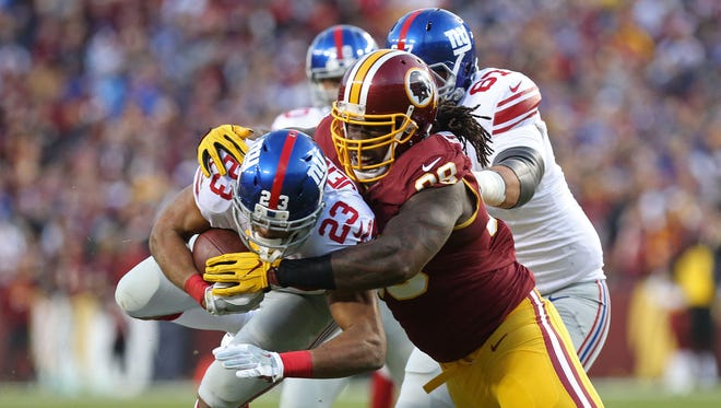 Giants running back Rashad Jennings (23) is tackled by Redskins defensive end Ricky Jean Francois (99) in the first quarter.