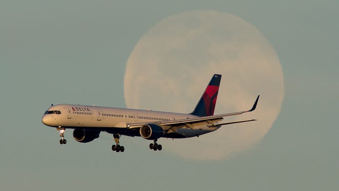 A Delta Air Lines Boeing 757 passes in front of a rising full moon at San Francisco International Airport in March 2017.