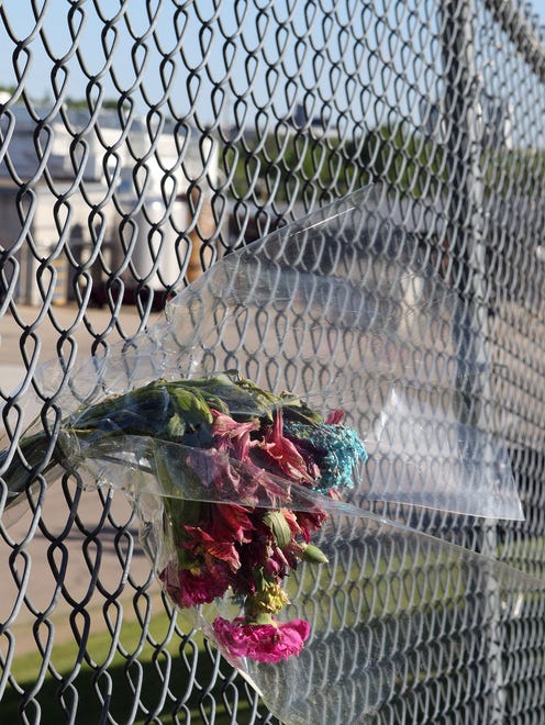 A bouquet of wilted flowers hangs in the fence surrounding Didion Milling days after an explosion ripped through the corn mill plant on May 31 killing three workers and injuring about a dozen others. A fourth worker died in the hospital from injuries sustained in the blast.