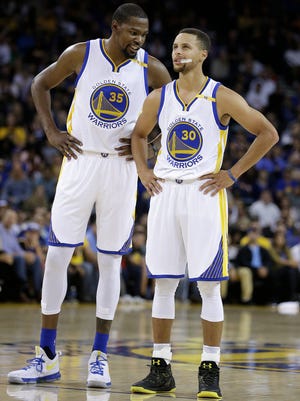 Golden State Warriors' Kevin Durant, left, speaks with Stephen Curry (30) during a recent game.