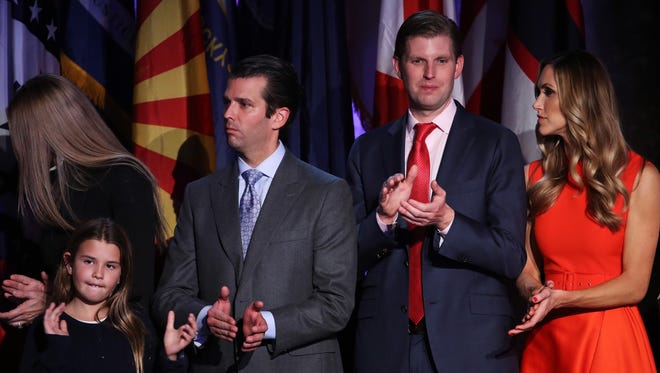 Donald Trump Jr., Eric Trump and his wife, Lara Yunaska, stand on stage and acknowledge the crowd during Donald Trump's election night event at the New York Hilton Midtown in the early morning hours of Nov. 9, 2016.
