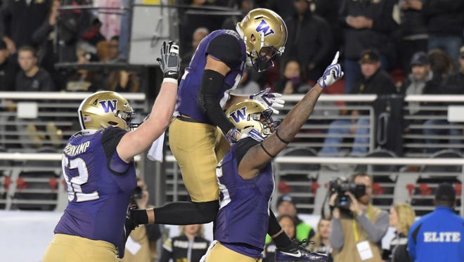 Washington tight end Darrell Daniels (15) celebrates his first-half TD catch with Aaron Fuller (12) and Jake Eldrenkamp (52).
