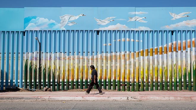 A man walks past the painted border fence in Agua Prieta, Mexico.