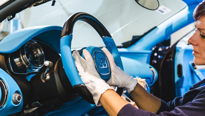 A Bugatti employee fits the steering wheel into place in the cabin of a Chiron.