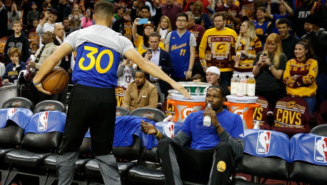 Golden State Warriors forward Kevin Durant gets a high five from guard Stephen Curry before facing the Cleveland Cavaliers.
