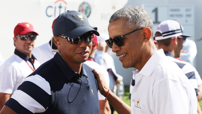 Tiger Woods speaks to former U.S. President Barack Obama on the first tee during foursome matches of the Presidents Cup at Liberty National Golf Club on Sept. 28.