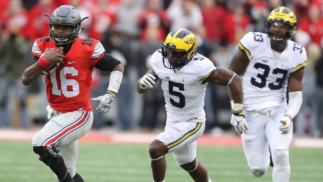 Michigan's Jabrill Peppers (5) and Taco Charlton pursue Ohio State's J.T. Barrett, who ran for a first down during the second half Saturday, Nov. 26, 2016 at Ohio Stadium.