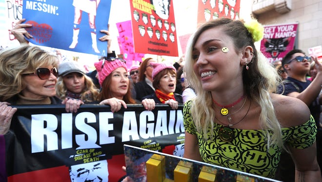 Miley Cyrus, right, marches during the Women's March on Saturday, in Los Angeles.  Ten of thousands of people took to the streets of Downtown Los Angeles for the march in protest after the inauguration of President Donald Trump. Women's Marches are being held in cities around the world.