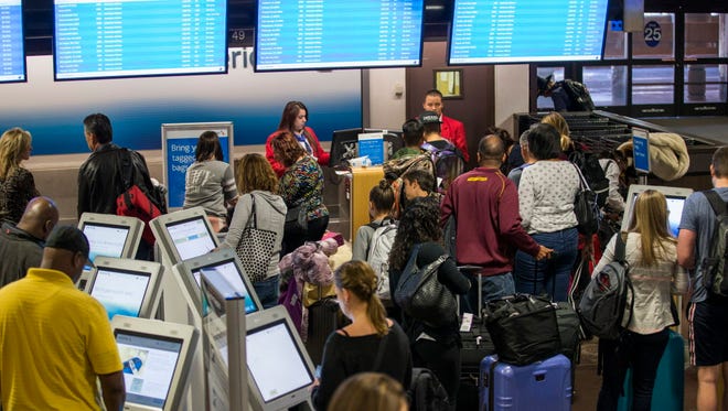 Travelers check in at American Airlines kiosks at Phoenix Sky Harbor November 24, 2015.