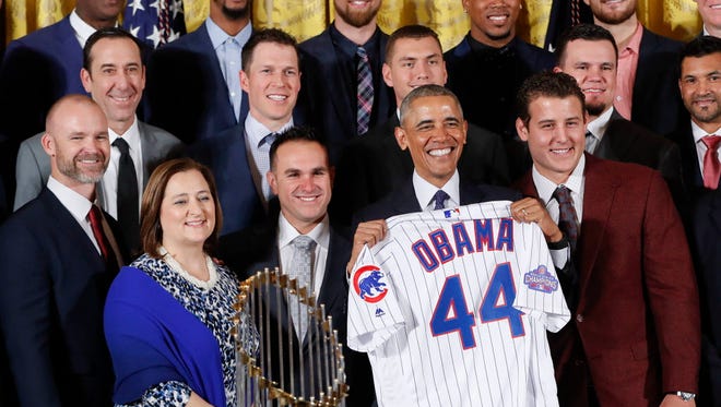 Obama holds up a personalized Chicago Cubs baseball jersey presented to him for a group photo during a ceremony in the East Room of the White House on Jan. 16, 2017, where the president honored the 2016 World Series Champion baseball team.