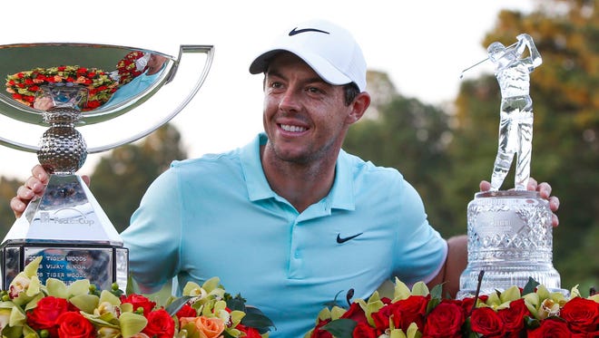 Rory McIlroy celebrates with the FedEx Cup trophy and the Tour Championship trophy.