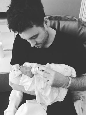 Christian music guitarist Nathan Johnson holds his newborn daughter Eilee. Johnson's wife, Megan, died Tuesday, June 27 from complications after child birth.