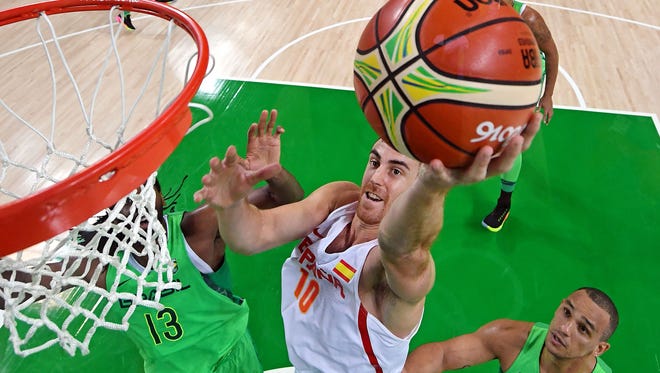 Spain power forward Victor Claver shoots against Brazil center Nene Hilario in basketball group play.