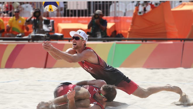 Josh Binstock of Canada reaches for the ball over teammate Samuel Schachter during their men's preliminary match against Brazil in Rio 2016 Summer Olympic Games at Beach Volleyball Arena.