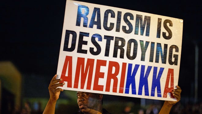 A man holds a sign during a protest on West Florissant Avenue in Ferguson, Mo., on Missouri on August 10, 2015.