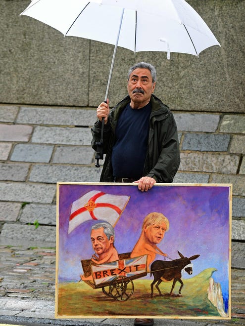 Satirical artist Kaya Mar poses with a Brexit-themed artwork depicting UK Independence Party leader Nigel Farage, left,  and former London Mayor Boris Johnson, in London as Britain holds a referendum on wether to stay in, or leave the European Union. Millions of Britons began voting Thursday in a bitterly-fought, knife-edge referendum that could tear up the island nation's EU membership and spark the greatest emergency of the bloc's 60-year history.