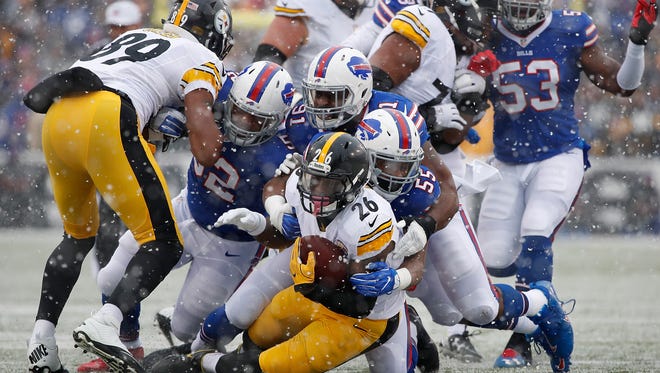 Pittsburgh Steelers running back Le'Veon Bell (26) is tackled by Buffalo Bills outside linebacker Jerry Hughes (55) and defensive end Leger Douzable (91) during the first quarter at New Era Field.
