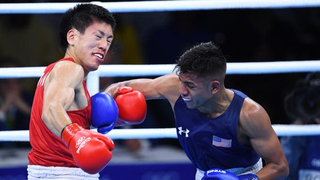 Carlos Zenon Balderas of the United States delivers a punch against Daisuke Narimatsu of Japan during the men's light preliminaries in the Rio 2016 Summer Olympic Games at Riocentro - Pavilion 6.