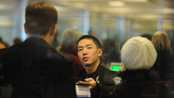 Customs agent Kevin Lin hands back passports and visas to arriving travelers at the primary checkpoint at Dulles International Airport on Feb. 23, 2012.
