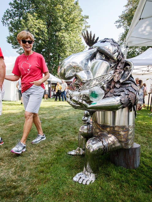 Ellie Hanson of Cedarburg admires a whimsical troll sculpture by artist James Sauer of Creative Illusions in Slinger during the 47th annual Oconomowoc Festival of the Arts in Fowler Park on Saturday, August 19, 2017.