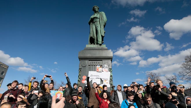 People surround Alexander Pushkin monument with a poster reading: 'Dimon (Prime Minister Dmitry Medvedev) Give Money Back,' in downtown Moscow on March 26, 2017. Russia's leading opposition figure Alexei Navalny and his supporters aim to hold anti-corruption demonstrations throughout Russia. But authorities are denying permission and police have warned they won't be responsible for 'negative consequences' or unsanctioned gatherings.