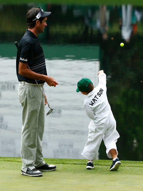 Bubba Watson watches as his son throws a ball in the lake during the Par 3 Contest.