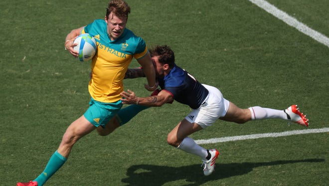 Cameron Clark of Australia looks to pass the ball as he is tackled by  Terry Bouhraoua of France during a rugby sevens match at Deodoro Stadium in the Rio 2016 Summer Olympic Games.