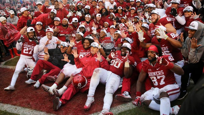 Oklahoma coaches and players take a team photo with the Big 12 championship trophy after beating Oklahoma State at Gaylord Family - Oklahoma Memorial Stadium.