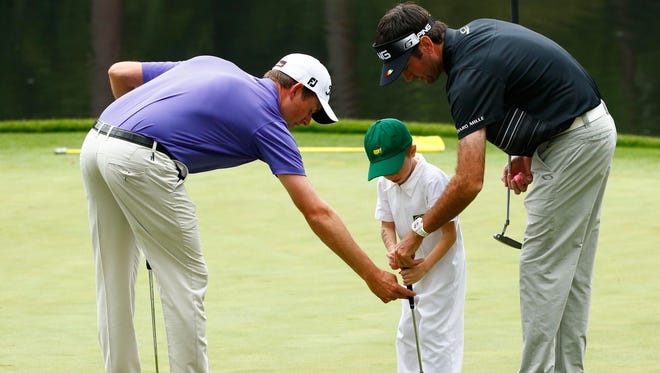Webb Simpson and Bubba Watson with Simpson's son on the ninth green during the Par 3 Contest.