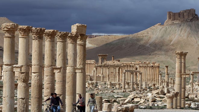 Syrian citizens ride their bicycles near ruins in the ancient city of Palmyra in this photo from 2014.