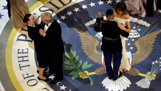 President Donald Trump dances with Navy Petty Officer 2nd Class Catherine Cartmell, front left, and first lady Melania Trump dances with Army Staff Sgt. Jose A. Medina, front right, at The Salute To Our Armed Services Inaugural Ball in Washington.