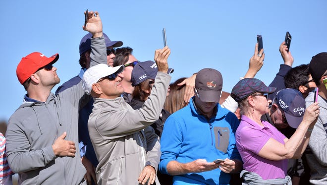 Fans hold up cell phones as Tiger Woods walks up to the 1st hole tee during the first round of the Farmers Insurance Open at Torrey Pines Municipal Golf Course on Jan. 27.
