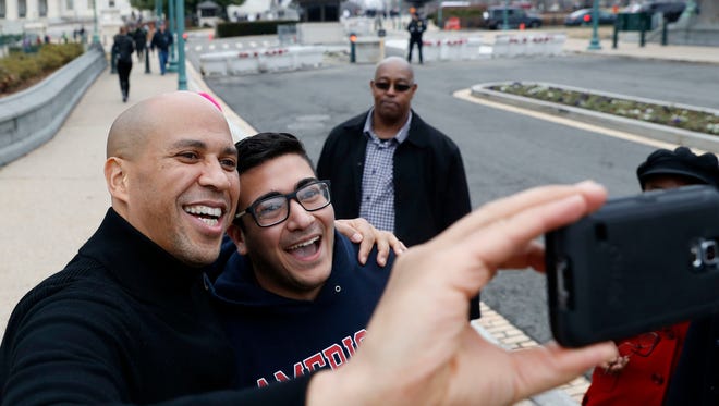 Sen. Cory Booker, D-N.J., left, takes a selfie with Abbas Iseahany, from Tenafly, N.J., an American University student, during the Women's March on Washington, Saturday.