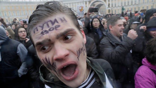 Protesters shout slogans at Dvortsovaya (Palace) Square in St. Petersburg, Russia on March 26, 2017. Thousands of people crowded in St. Petersburg on Sunday to protest the Russian government. The writing on the protestor's face reads 'Putin is a thief.'