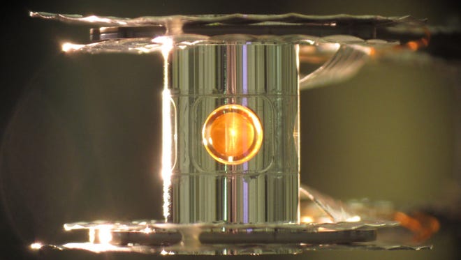 This undated image provided by the Lawrence Livermore National Laboratory shows a deuterium and tritium capsule, sphere in window at center, inside a cylindrical hohlraum container about 0.4 inches tall. In research reported Wednesday, Feb. 12, 2014 by the journal Nature, scientists say they've taken a key step toward harnessing nuclear fusion as a new way to generate power, an idea that has been pursued for decades. In tests, 192 laser beams briefly fired into the small gold cylinder which held the two kinds of hydrogen. The energy from the lasers kicked off a process that compressed the ball by an amount akin to squeezing a basketball down to the size of a pea. That created the extremely high pressure and temperatures needed to get the hydrogen atoms to fuse.