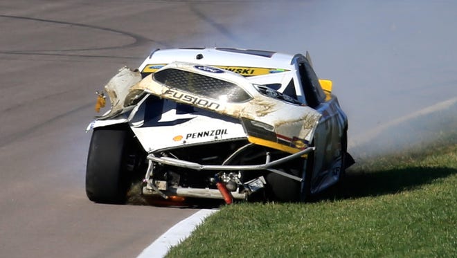 Brad Keselowski drives his mangled race car to pit road after sliding through the grass at Kansas Speedway.