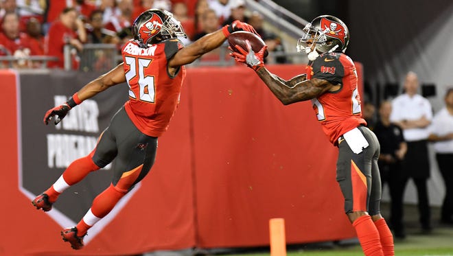 Buccaneers defensive back Ryan Smith (29) downs the ball on a punt after teammate Josh Robinson (26) knocked it back on the field of play  in the second half.