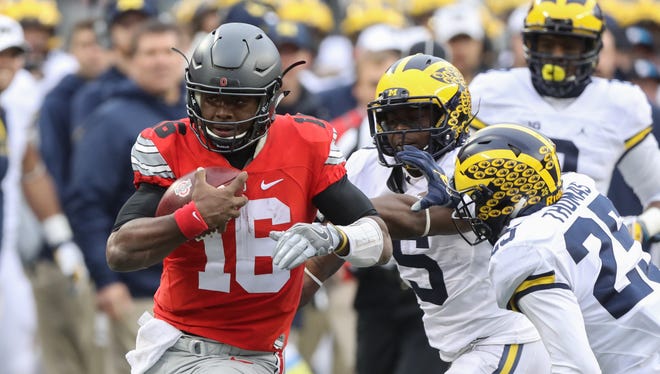 Michigan's Jabrill Peppers (5) and Dymonte Thomas pursue Ohio State's J.T. Barrett, who ran for a first down during the second half Saturday, Nov. 26, 2016 at Ohio Stadium.