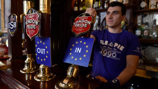 A bartender pulls a pint of beer decorated with EU Referendum beer taps in a pub in London on June 22, 2016.