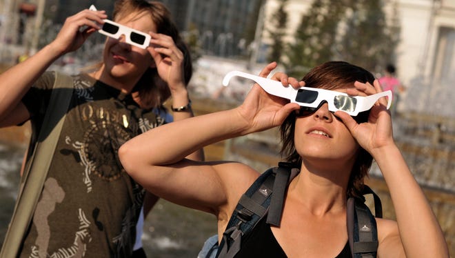 People check their eclipse glasses ahead of a solar eclipse in the Siberian city of Novosibirsk on Thursday, July 31, 2008. The Great American Eclipse of Aug. 2017 is leading to a tourist boon from Oregon to South Carolina.