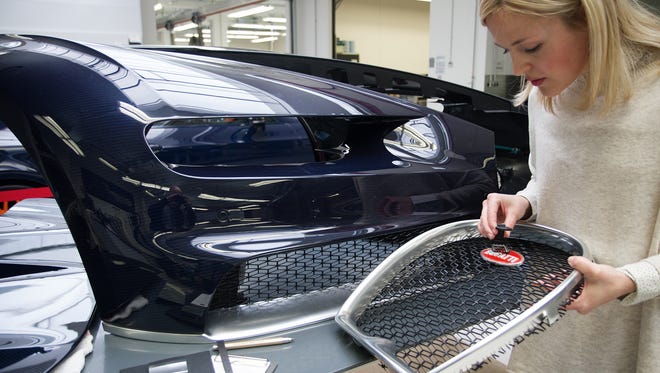 A Bugatti executive handles the front grill with the logo for Bugatti at the front and center of the vehicle.