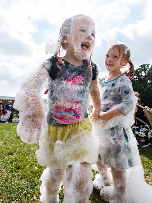 Four-year-old Aubrey Fleischfresser (left) of Mayville heads back for more fun in the Crosspoint Community Church bubble tent during Oconomowoc Kid's Fest at Roosevelt Park on Tuesday, Aug. 15, 2017. The annual event features games, entertainment, music, inflatables, arts and crafts, food and more.