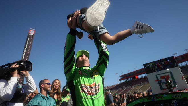 Kyle Busch celebrates his 200th combined NASCAR national series win by tossing his son Brexton in the air in Auto Club Speedway victory lane.