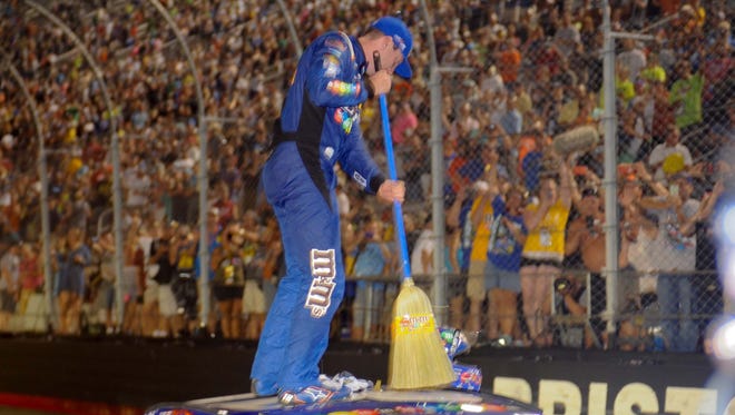 Kyle Busch does a little housekeeping on top of his No. 18 Toyota after winning the NASCAR Cup Series race to complete the sweep at Bristol Motor Speedway on Aug. 19.