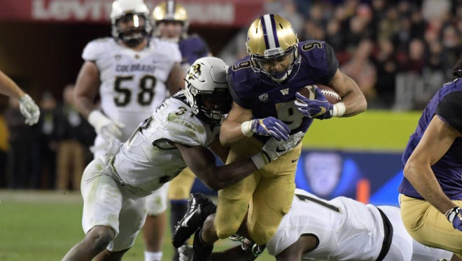 Washington running back Myles Gaskin (9) fights for yardage between a pair of Colorado defenders during the second half.