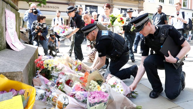 Police offices add to the flowers for the victims of Monday night pop concert explosion, in St Ann's Square, Manchester, on May 23, 2017.