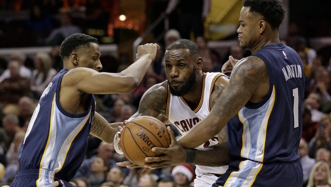 Cleveland Cavaliers' LeBron James, center, drives between Memphis Grizzlies' Troy Williams, left, and Jarell Martin in the second half of an NBA basketball game, Tuesday, Dec. 13, 2016, in Cleveland. The Cavaliers won 103-86. (AP Photo/Tony Dejak)