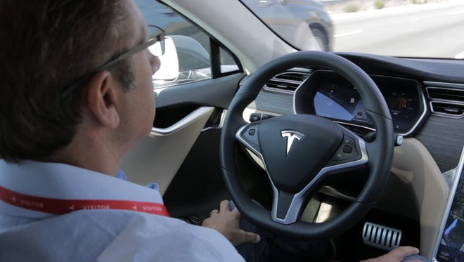 USA TODAY tech reporter Marco della Cava takes his hands off the wheel of a Tesla Model S sedan while driving down the 280 Freeway north of the Tesla's headquarters in Palo Alto, Calif.